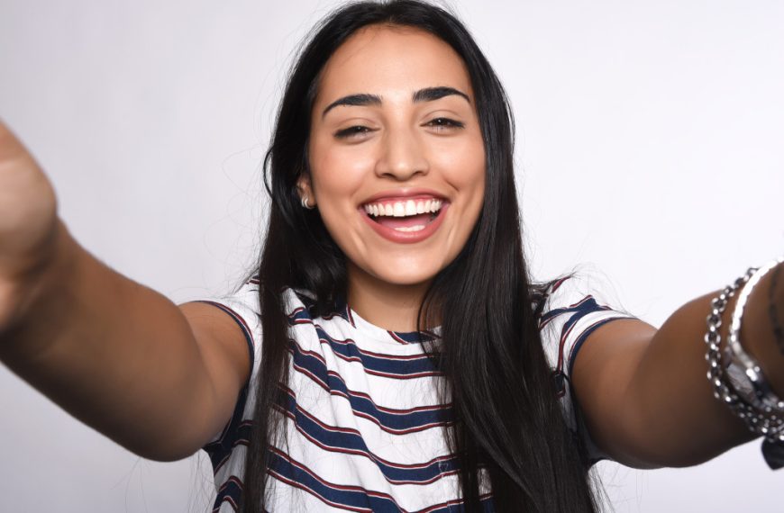 woman smiling with arms out representing confidence with white background