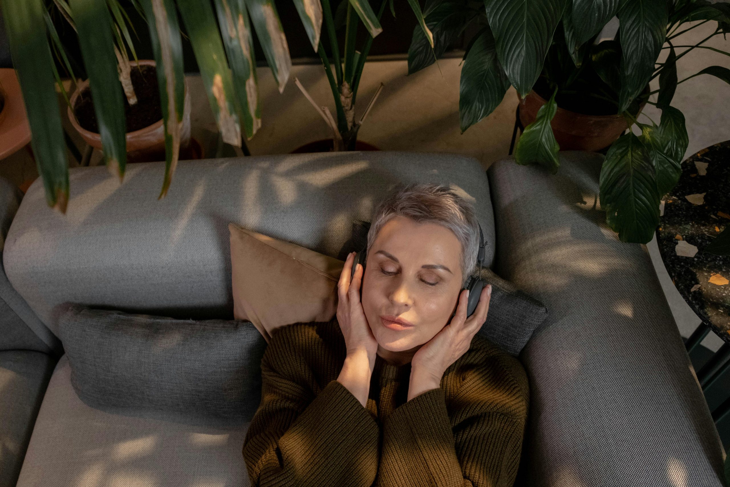 woman wearing headphones, lying on a couch and meditating